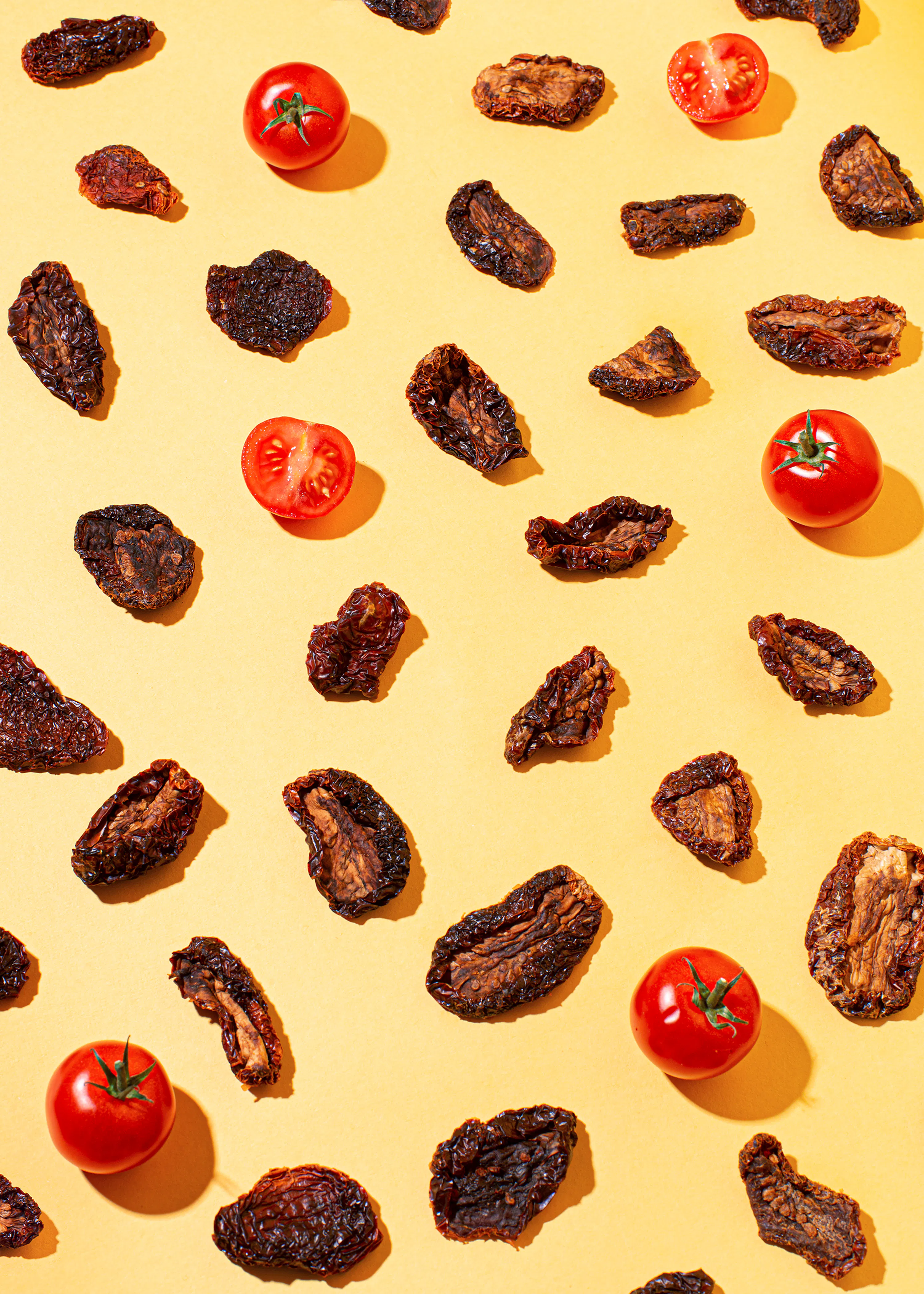 getrocknete Tomaten und Tomatenscheiben auf gelbem Hintergrund